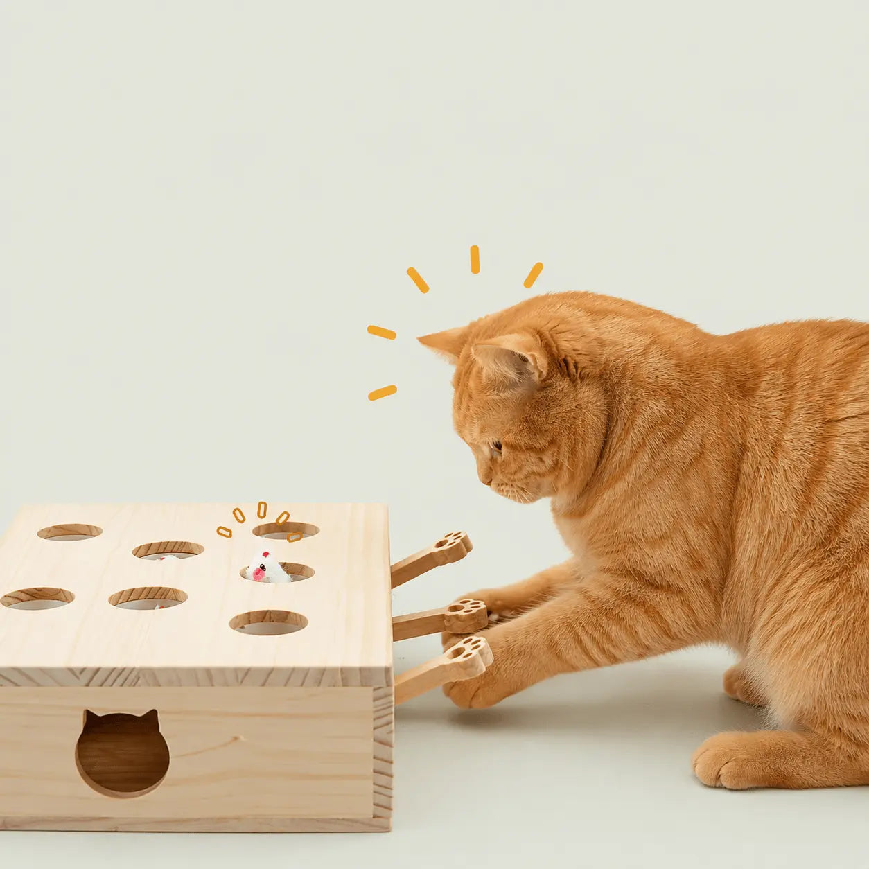 Chat roux fixant une souris en peluche dans le jouet en bois, avec effet de surprise