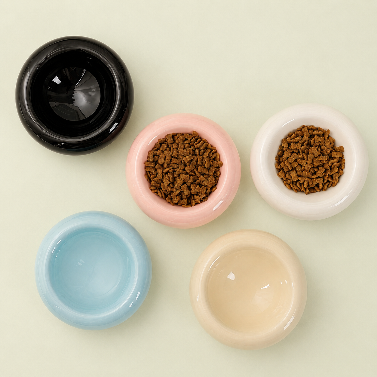 Vue de dessus de cinq bols donut pour chat en céramique : noir, rose, blanc, bleu et crème