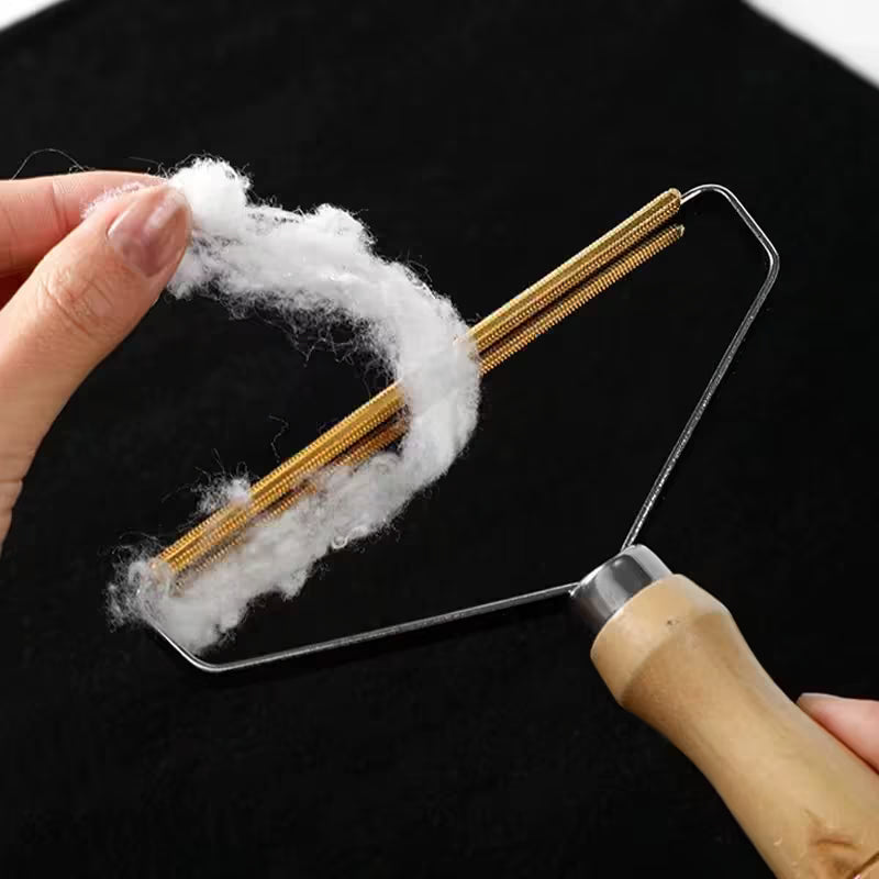 Gros plan sur les lames dorées d'un rasoir à peluches manuel chargé de poils blancs retirés d'un tissu noir