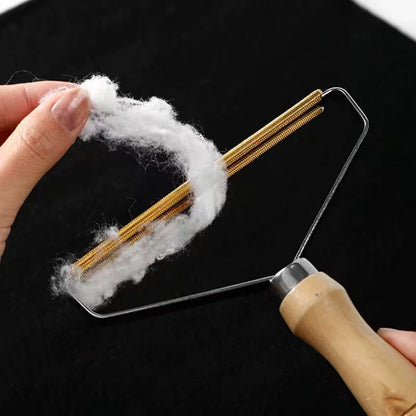 Gros plan sur les lames dorées d'un rasoir à peluches manuel chargé de poils blancs retirés d'un tissu noir